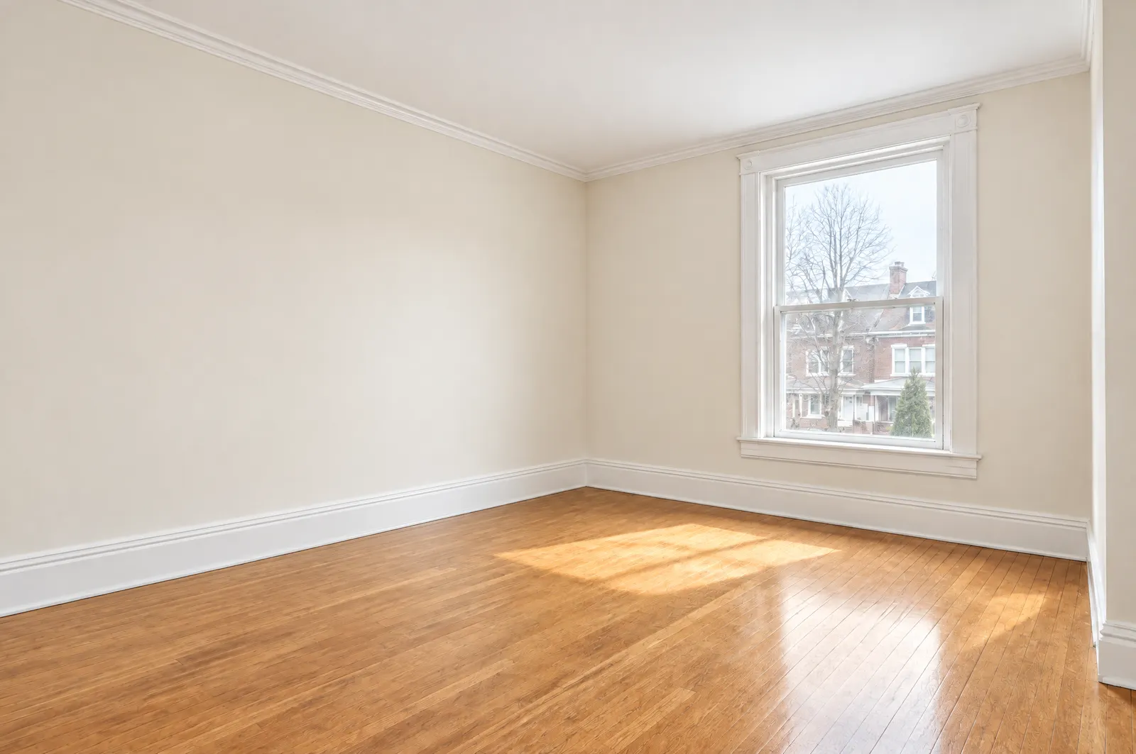 The same living room after: smooth warm-white walls, crisp white trim, refinished oak floor